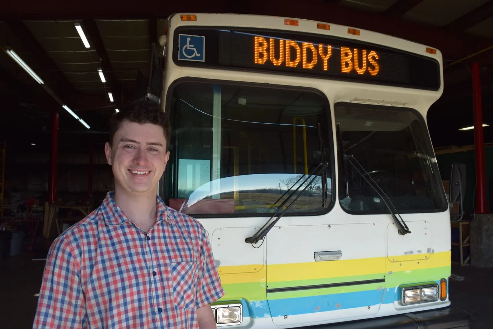 Jordan standing beside the Buddy Bus inside the BuildX shop.